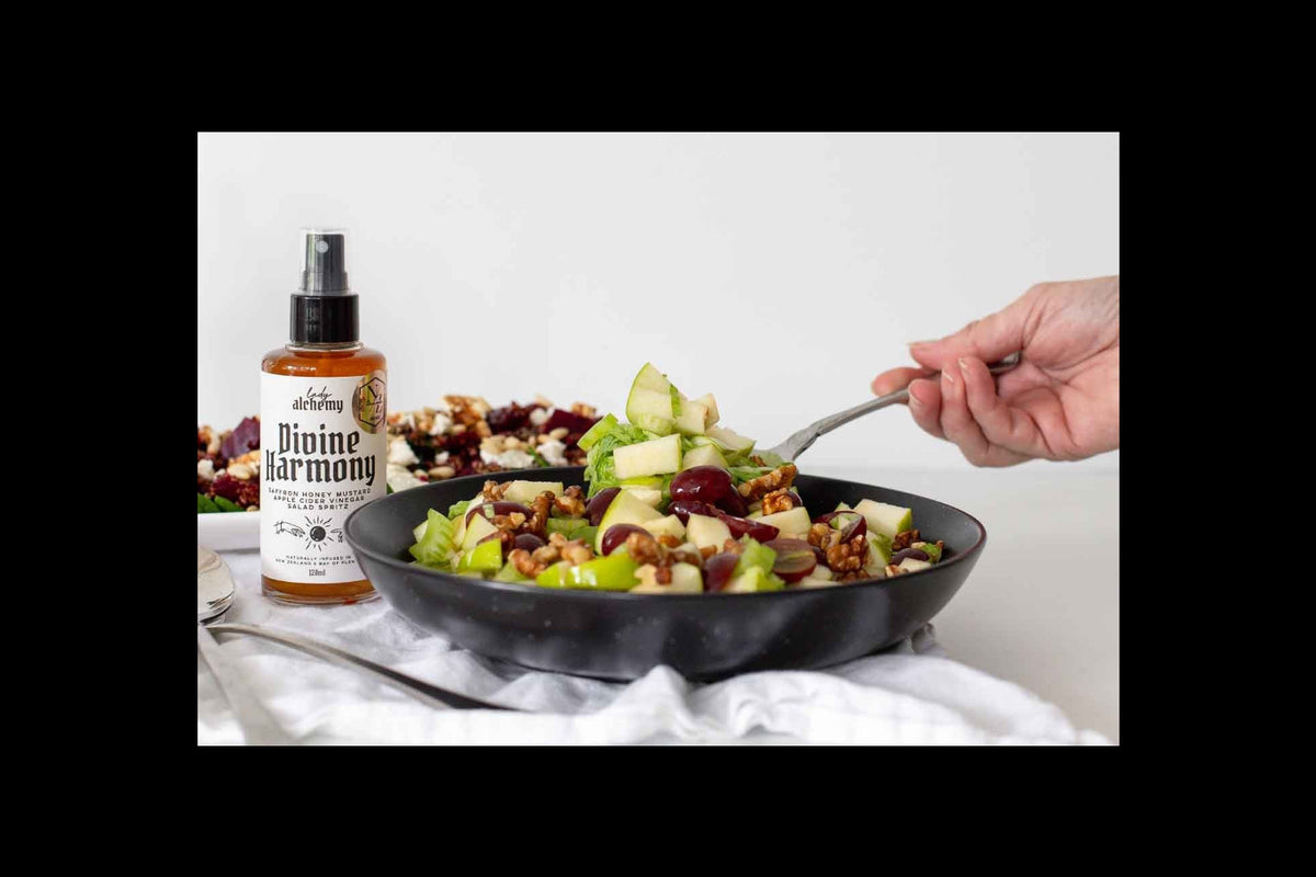 Person holding a fork over a salad with a bottle of Divine Harmony dressing on a white background